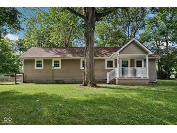 Charming ranch style home featuring neutral siding, a cozy front porch, and a mature tree in the front yard at 7141 E Pleasant Run Pkwy S Dr, Indianapolis, IN 46219