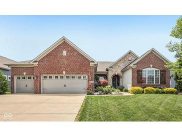 Charming brick home featuring a three car garage, manicured lawn and colorful landscaping in front at 19281 Scofield Ridge Blvd, Westfield, IN 46074