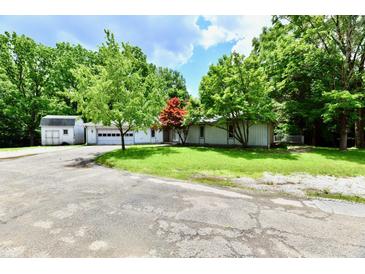 Charming single-story home featuring lush greenery, an attached garage, and a private driveway at 4115 Tansel Rd, Indianapolis, IN 46234