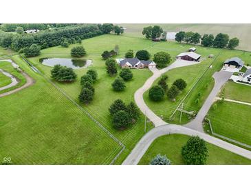 Expansive aerial view of estate with lush lawns, mature trees, pond, and elegant brick home with pool and winding driveway at 4670 N 600 E, Franklin, IN 46131