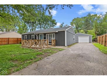 Charming gray home with a wooden porch, well-maintained lawn, and long driveway leading to a detached garage at 5367 Penway St, Indianapolis, IN 46224