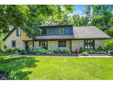 Charming stone-clad home featuring a lush green lawn and meticulously landscaped flower beds at 8924 Stormhaven Ct, Indianapolis, IN 46256