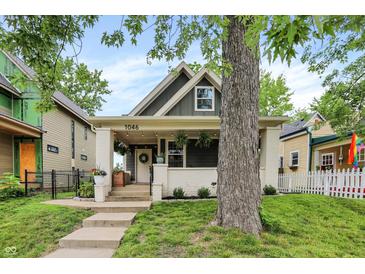 Charming home featuring a covered porch, brick accents, and a beautifully landscaped front yard at 1046 N Hamilton Ave, Indianapolis, IN 46201