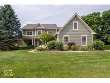 Charming two-story home boasts a lush lawn, mature trees, and inviting curb appeal at 10865 Fairwoods Dr, Fishers, IN 46037