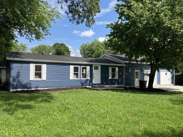 Charming blue home featuring white trim, lush lawn, and mature trees, offering great curb appeal at 221 N 9Th St, Elwood, IN 46036