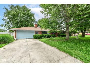 Charming single-story brick home with a blue garage door and a long driveway, surrounded by mature trees and greenery at 3636 Oakwood Dr, Anderson, IN 46011