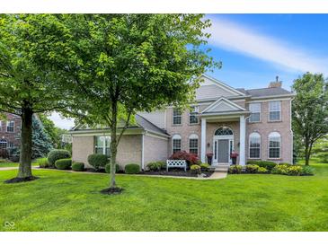 Charming brick home features a well-manicured lawn, mature tree, and inviting front porch with white columns at 3345 Kilkenny Cir, Carmel, IN 46032