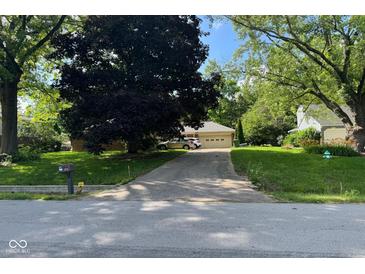 Charming home with an attached garage and a well-maintained lawn, shaded by mature trees along the driveway at 3440 W 46Th St, Indianapolis, IN 46228
