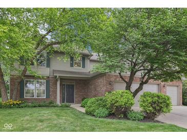 Charming two-story home with brick and vinyl siding, complemented by lush landscaping and a three-car garage at 9643 Cypress Way, Carmel, IN 46032