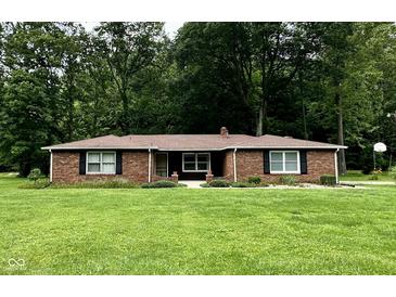 Charming brick ranch home featuring a well-manicured lawn and beautiful, mature trees offering shade and privacy at 1980 S Arthur Rd, Paragon, IN 46166