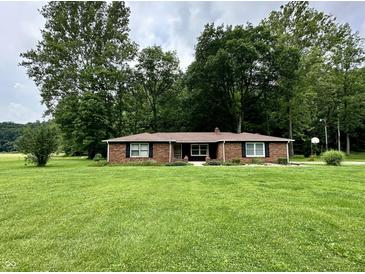 Charming brick ranch home with a well-manicured lawn, mature trees, and classic black shutters at 1980 S Arthur Rd, Paragon, IN 46166
