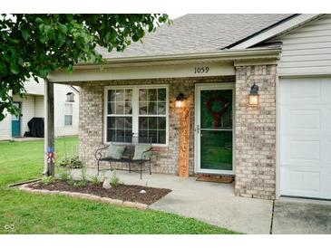 Welcoming front of this home with an inviting bench, a welcome sign, and charming lanterns at 1059 Wild Ivy Trl, Franklin, IN 46131