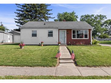 Charming single-story home with a well-manicured lawn and American flags lining the sidewalk leading to the front door at 206 Allen Ln, Greenfield, IN 46140