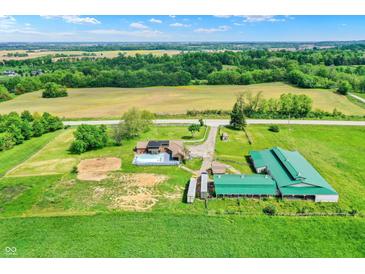 Expansive aerial view of a farm featuring a house, pool, barn, and lush green fields with mature trees at 7165 W State Road 252 W Rd, Edinburgh, IN 46124