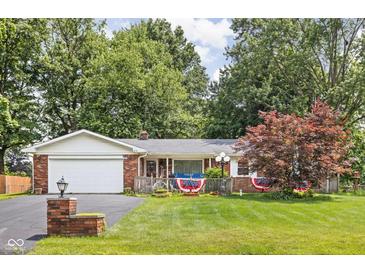 Charming single-story brick home featuring an attached garage and a well-maintained front yard and patriotic decor at 7651 Sherry Ln, Brownsburg, IN 46112