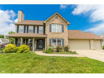 Charming two-story brick home featuring a manicured lawn, covered porch, and attached two-car garage at 7710 Samuel Dr, Indianapolis, IN 46259