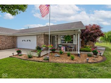 Charming brick home featuring a cozy front porch and landscaped garden, complete with an American flag at 7911 Bentley Commons Dr, Indianapolis, IN 46259