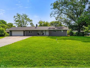 Charming single-story home featuring a lush green lawn, attached garage, and a welcoming front porch at 8025 Meadow Ln, Indianapolis, IN 46227