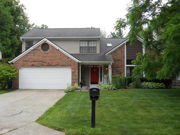 Charming two-story home with well-manicured lawn and a two-car garage and brick facade, plus a red door at 1067 Barley Cir, Carmel, IN 46032