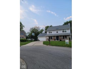 Charming two-story home boasts a lush front yard and long driveway leading to an attached garage at 922 Eagle Brook Dr, Shelbyville, IN 46176