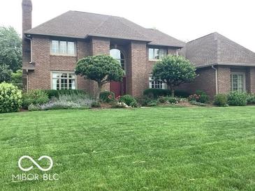Beautiful brick home with a large front lawn and meticulously maintained landscaping at 1273 Helford Ln, Carmel, IN 46032