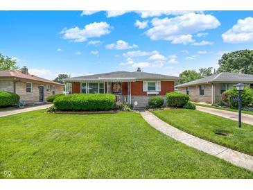 Charming brick ranch-style home with a well-manicured lawn and mature landscaping under a bright sky at 3322 N Riley N Ave, Indianapolis, IN 46218