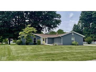 Charming single-story home with well-manicured lawn, mature trees and bright yellow front door at 540 Lazy Ln, Greenwood, IN 46142