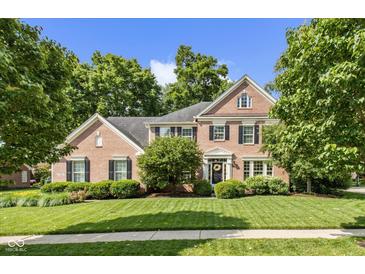 Beautiful two-story brick home with manicured lawn, mature trees, and classic architectural details at 5997 Hollythorn Pl, Carmel, IN 46033