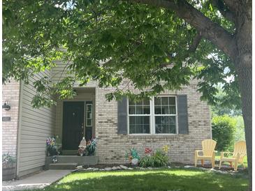 Charming brick home with well-maintained lawn, mature tree, and cheerful decorative details at 6532 Amherst Way, Zionsville, IN 46077