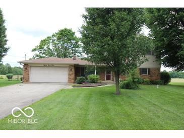 Inviting front yard view of home with a manicured lawn, mature trees, and attached two-car garage at 8905 Maze Rd, Indianapolis, IN 46259