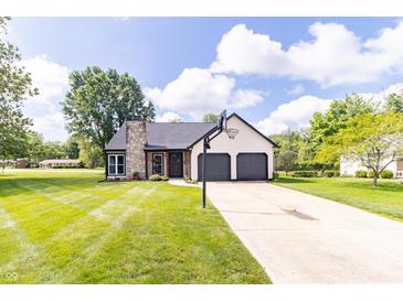 Charming home featuring an attached two-car garage, well-manicured lawn and basketball hoop on the driveway at 8925 Sunburst Cir, Indianapolis, IN 46227