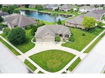 A beautiful aerial view of a brick home that features a pond, large yard, and three-car garage at 182 Southwind Ln, Greenwood, IN 46142