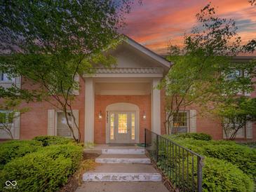 Stunning brick home featuring a covered entrance with white pillars and beautifully landscaped front yard at 7317 Lions Head Dr # A, Indianapolis, IN 46260