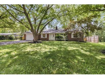 Charming one-story brick home featuring a well-manicured lawn and mature trees providing ample shade at 8246 Windcombe Blvd, Indianapolis, IN 46240