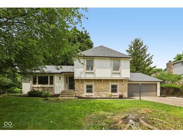Charming home with a stone facade and well-maintained lawn with mature trees and an attached two car garage at 10778 Haverstick Rd, Carmel, IN 46033