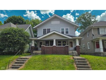Charming two-story home featuring a covered front porch with brick accents and a well-maintained lawn at 1427 N Lasalle St # 1427, Indianapolis, IN 46201