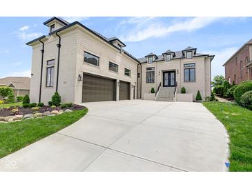 Stunning brick home with three-car garage and manicured lawn with elegant landscaping and concrete driveway at 16512 Grand Cypress Dr, Noblesville, IN 46060