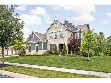Beautiful two-story home with a stone and siding exterior, manicured lawn, and mature trees at 3720 Abney Highland Dr, Zionsville, IN 46077