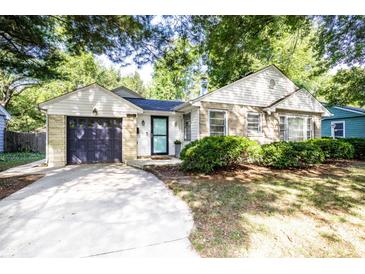 Charming home featuring a stone and vinyl exterior, inviting curb appeal, attached garage, and manicured front lawn at 5736 Primrose Ave, Indianapolis, IN 46220