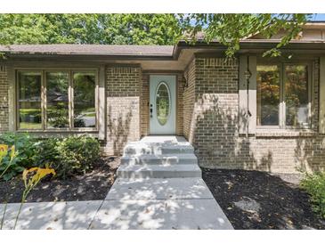 Brick home entrance with an oval window door, concrete steps, and dark mulch landscaping at 604 Oak Blvd W Dr, Greenfield, IN 46140