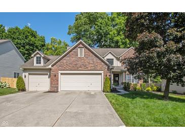 Charming two-story brick home with a well-manicured lawn and a spacious three-car garage and driveway at 6465 Robinsrock Dr, Indianapolis, IN 46268