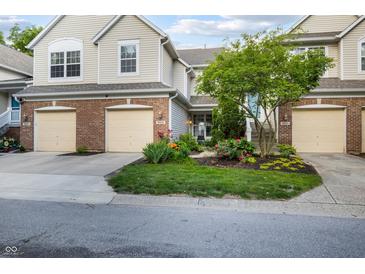 Charming townhome with a brick facade, attached garage, and well-manicured lawn with colorful landscaping at 9525 Longwell Dr, Indianapolis, IN 46240