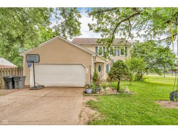 Charming two-story home with tan siding, attached garage and well-manicured lawn and garden in front at 1357 Brownswood Dr, Brownsburg, IN 46112