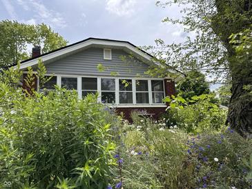 Charming home with a well-manicured yard featuring lush greenery and a variety of colorful flowers at 1433 N Colorado Ave, Indianapolis, IN 46201