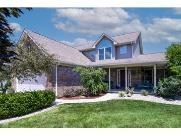 Charming two-story home featuring a manicured lawn, a brick facade and an inviting covered porch at 2756 Bluebell E Ct, Columbus, IN 47201