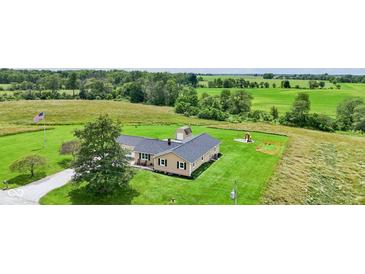 Picturesque aerial view of home with large yard, American flag and playset surrounded by beautiful greenery at 3450 Clay Rd, North Salem, IN 46165