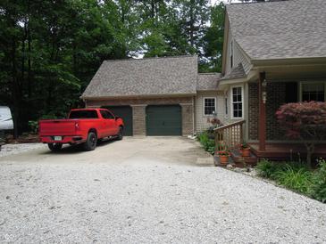 Charming home featuring a two-car garage, lovely landscaping, and a red truck in the driveway at 4521 Tulip N Dr, Martinsville, IN 46151