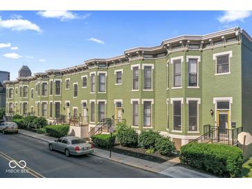 Row of green painted townhomes with bay windows, black iron fences, and manicured landscaping at 914 N Alabama St, Indianapolis, IN 46202