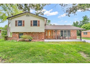Charming two-story home featuring a well-manicured lawn and a covered front porch with rocking chairs at 2823 Tulip Dr, Indianapolis, IN 46227