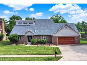Beautiful brick home featuring an attached garage, mature landscaping, and a well-manicured lawn at 369 Rodeo Dr, Indianapolis, IN 46217